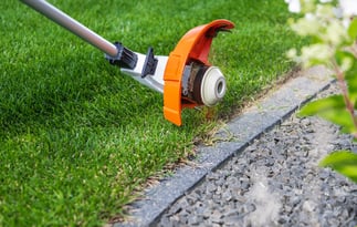 trimming-grass-along-a-stone-border-in-a-well-kept-2025-03-16-20-31-20-utc